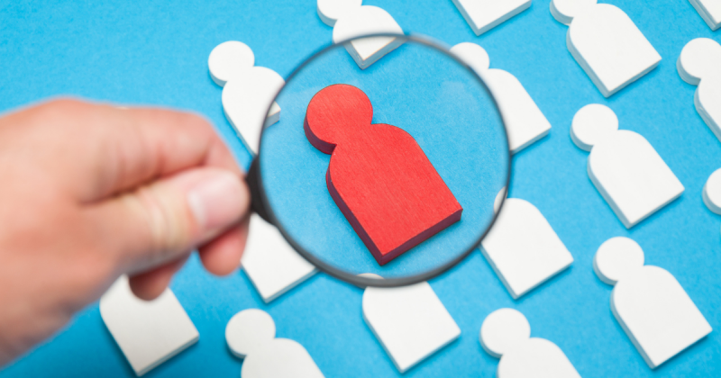 Set against a bright blue background, the image depicts white outlines of people with a single red person in the middle, showing how executive researchers find the right candidate in a sea of qualified individuals.